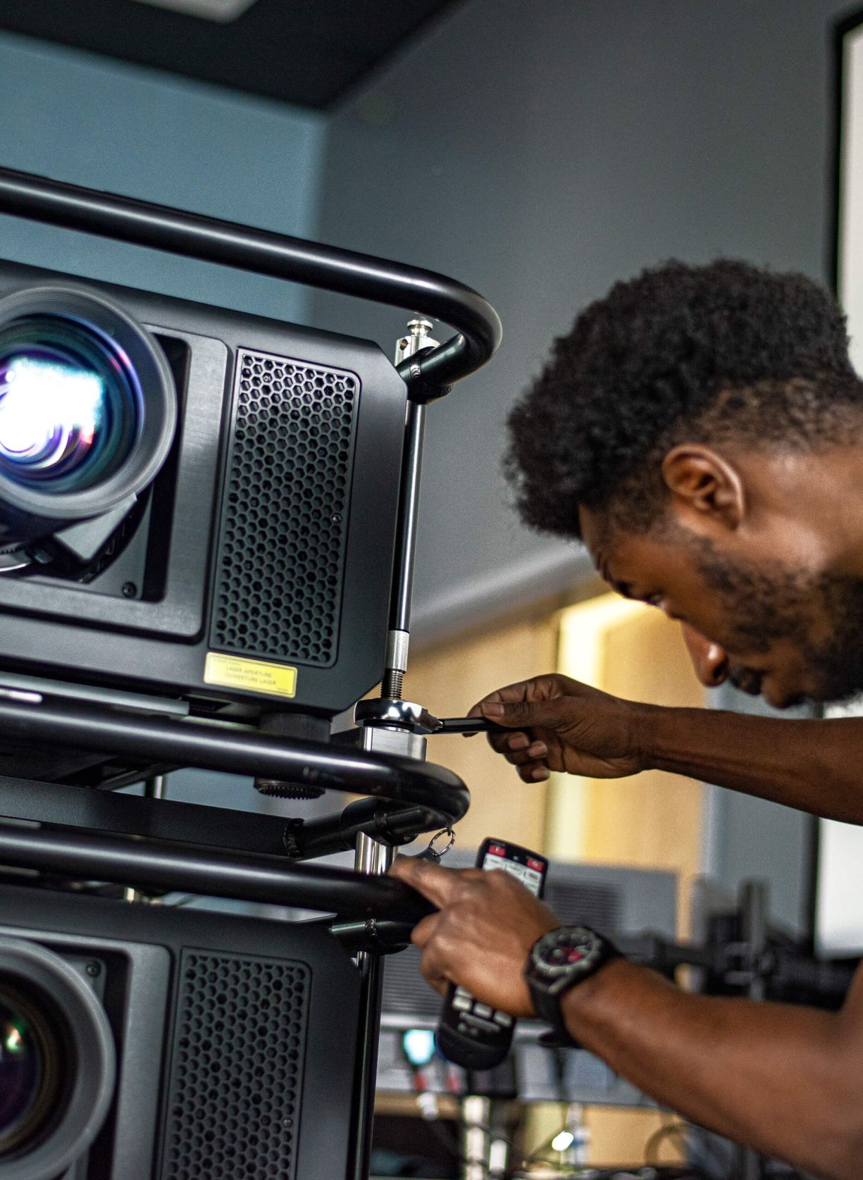 A man is working on a projector in a room.