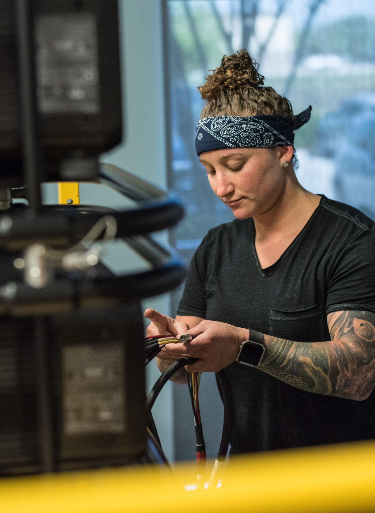 A woman wearing a bandana is working on a machine.