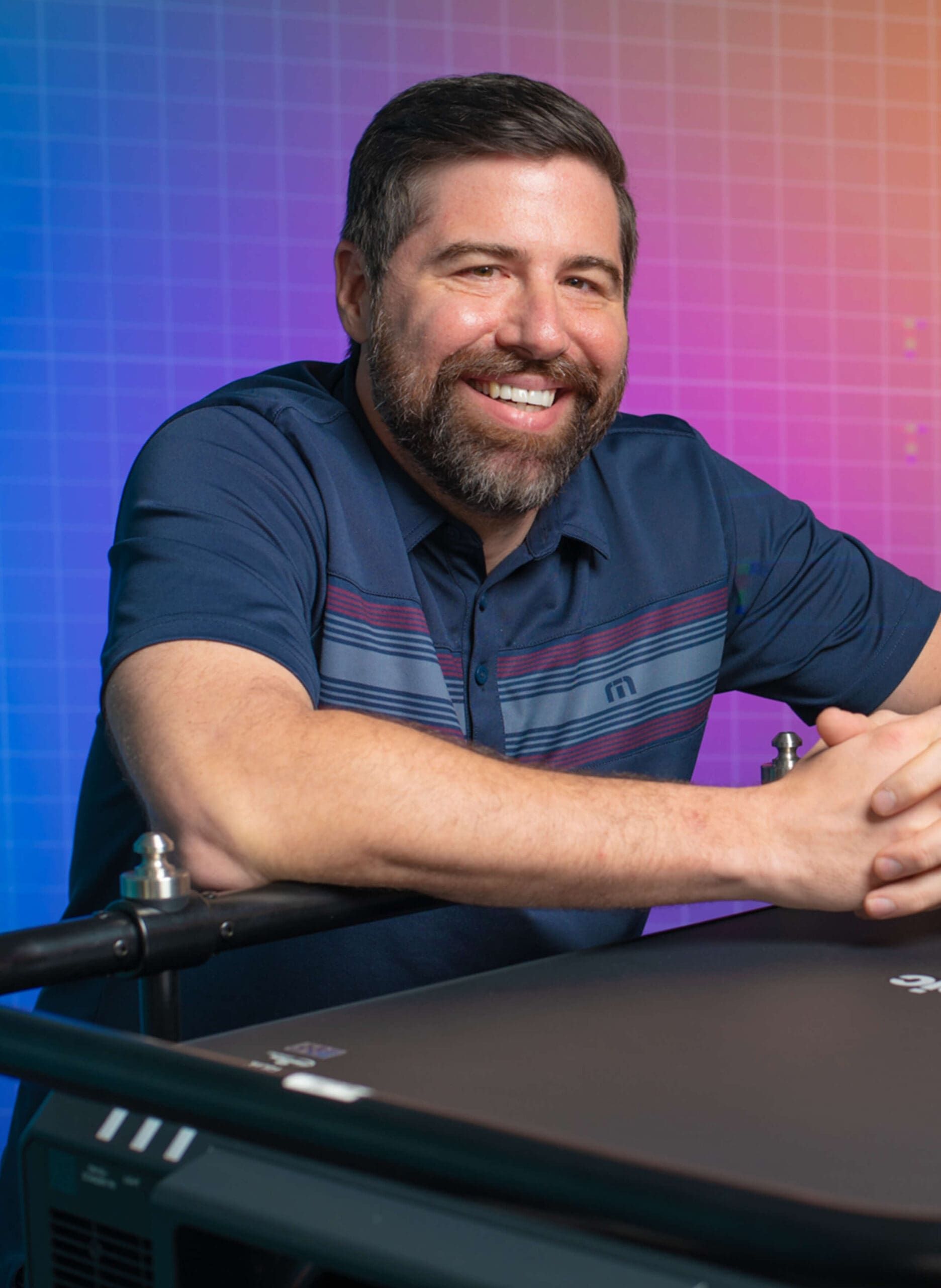 A man sitting at a desk with a colorful background.