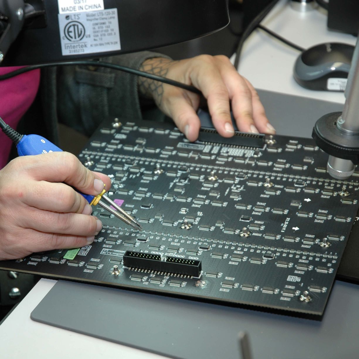 A person is working on a circuit board.